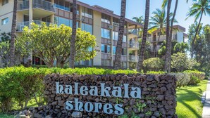 Un hotel de varios pisos con balcones, palmeras y un letrero que dice "haleakala shores".