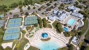 An aerial view of a sports complex with multiple tennis courts, a swimming pool, and a large covered area. - Windswept Dr  Condo in a quiet, golf course community close to Rehoboth Beach (Millsboro)