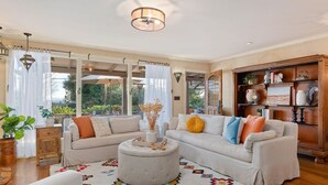 A spacious living room with two sofas, a round ottoman, and a colorful rug. - Spacious Mesa Home with Great Outdoor Patio and Ocean Views! (Santa Barbara)