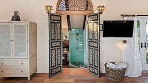 A room with a traditional arched doorway, a television mounted on the wall, and a wicker basket on the floor. - Spacious Mesa Home with Great Outdoor Patio and Ocean Views! (Santa Barbara)