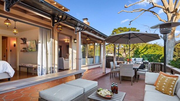 An outdoor patio with wicker furniture, a dining table, and a grill. - Spacious Mesa Home with Great Outdoor Patio and Ocean Views! (Santa Barbara)
