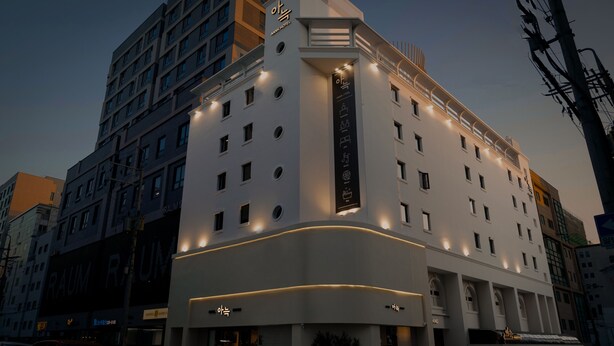 A modern hotel with a prominent entrance, multiple floors, and illuminated windows. - Anook Hotel Suwon Ingye (Suwon)