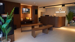A modern reception area with a wooden reception desk, a television mounted on the wall, and a sign that reads "MUSIC LOUNGE". - Anook Hotel Suwon Ingye (Suwon)