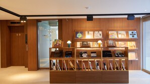 A reception area with a wooden reception desk, a digital clock, and framed artwork on the wall. - Anook Hotel Suwon Ingye (Suwon)