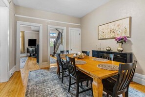 A dining area with a wooden table, black chairs, and a patterned rug.