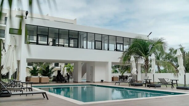 A modern hotel with a large pool, outdoor seating, and palm trees. - Downtown Punta Cana, Republica Dominicana.

 (Punta Cana)