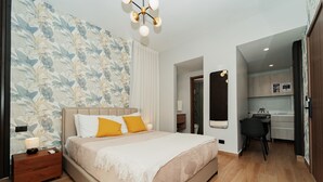 A modern bedroom with a large bed, a nightstand, a desk, and a kitchenette. - Downtown Punta Cana, Republica Dominicana.

 (Punta Cana)