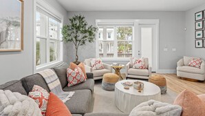 Un salon avec un canapé gris, deux fauteuils, une table basse et une plante en pot.