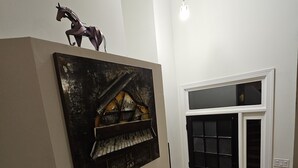 A hallway with a black door, a wall-mounted artwork, and a staircase. - Private Raleigh Bungalow Retreat near Downtown Raleigh (Raleigh)