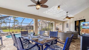 An outdoor patio with a dining table, chairs, and a ceiling fan. - Golf Course View! Heated Pool - Villa Fairway to Florida - Roelens Vacations (Cape Coral)