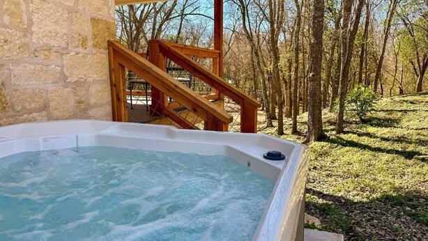 A hot tub with a wooden staircase leading to a deck, surrounded by a forested area. - High Street Cottage | Hot Tub | Great View (Comfort)