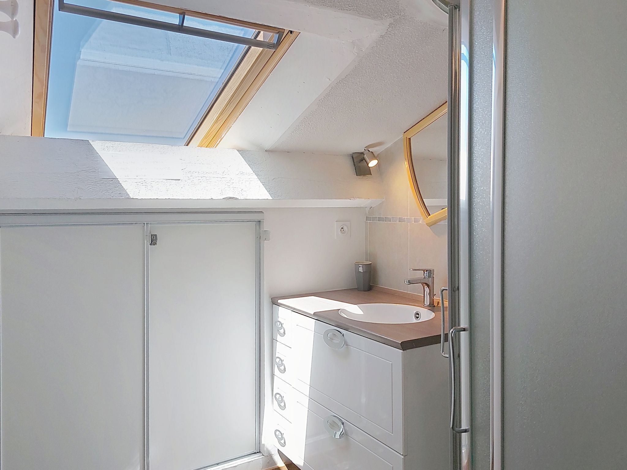 Baño con tragaluz, lavabo y espejo.