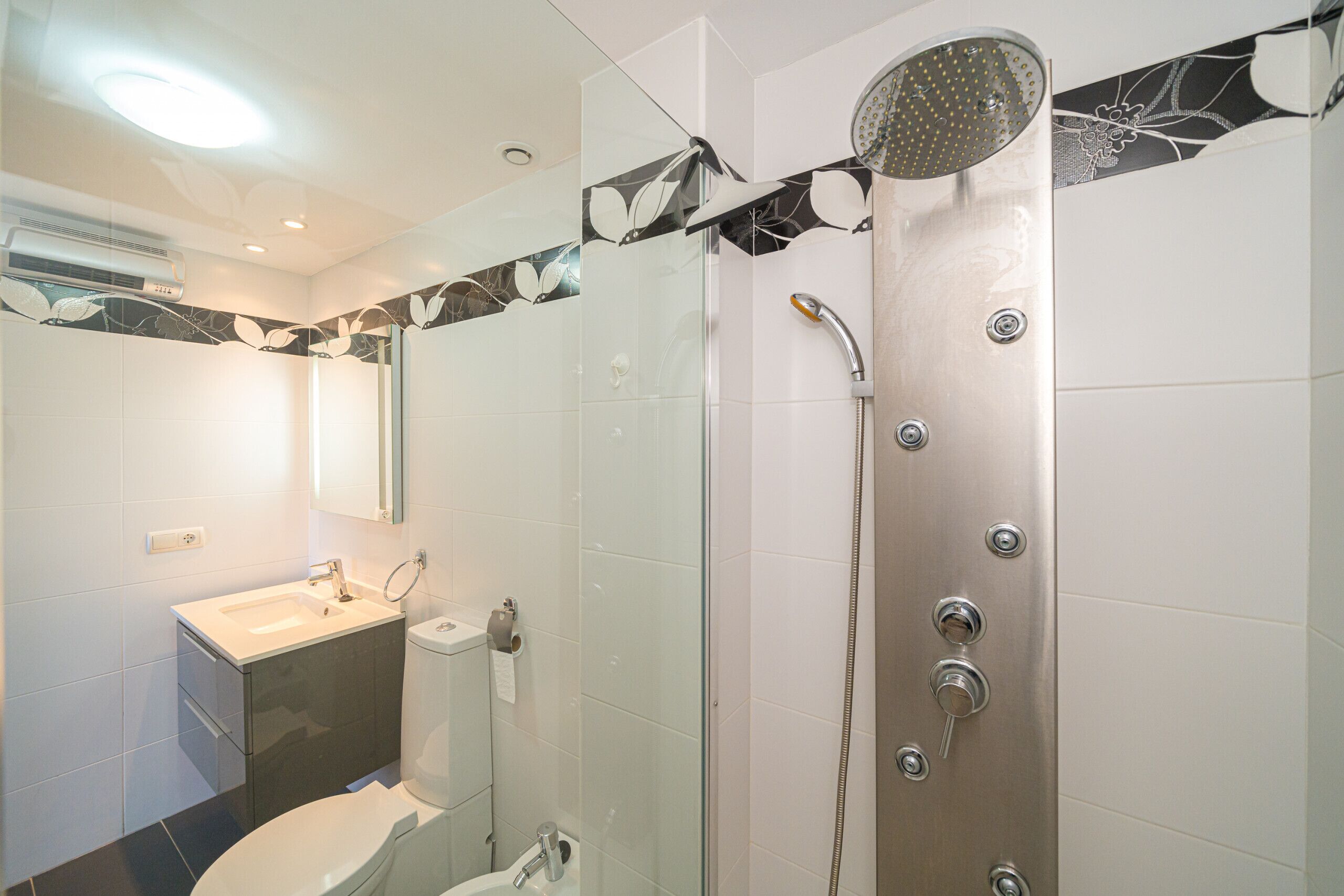 A modern bathroom with a glass-enclosed shower, a sink, and a toilet.