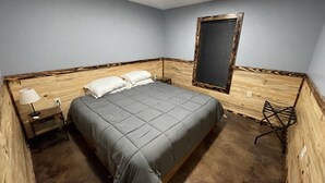 A bedroom with a bed, a nightstand, a lamp, a window with blinds, and a chair.