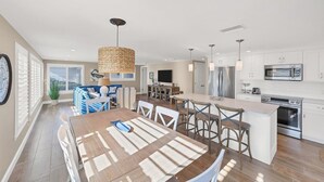 Une cuisine spacieuse avec des meubles blancs, des appareils en acier inoxydable et un îlot central.