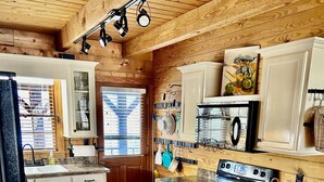 Una cucina con pavimento in legno, mobili bianchi, un fornello e un lavello.