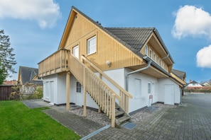 A two-story house with a wooden staircase, a garage, and a paved driveway. - Strandbrise - Ferienwohnung Strandbrise (Koserow)