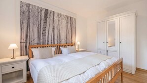 A bedroom with a bed, nightstands, a wardrobe, and a large wall mural. - Reni - Idyllisches Erdgeschoss-appartement Terrasse & Strandnah (Koserow)