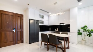 Eine moderne Küche mit Essbereich, ausgestattet mit einem schwarzen Kühlschrank, weißen Schränken und einer Holztür.