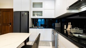 Eine moderne Küche mit weißen Schränken, einem schwarzen Kühlschrank und Edelstahlgeräten.