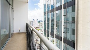 Ein Balkon mit Metallgeländer, einer Glastür und Blick auf andere Gebäude.