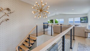 Un interior moderno con una escalera, una lámpara colgante y vistas al exterior.