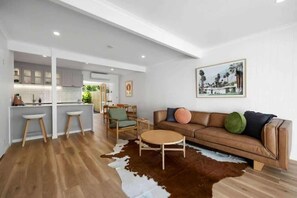 A modern living room with a brown leather sofa, a round coffee table, and a cowhide rug.