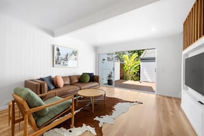 A modern living room with a leather sofa, a wooden chair, a round coffee table, and a cowhide rug.