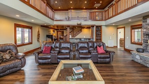 A spacious living room with a high ceiling, a fireplace, and a staircase leading to an upper level.