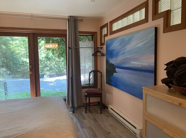 A bedroom with a bed, a chair, a painting, and a dresser. - The Hobbit on Canopy Ridge Gabriola (Gabriola)