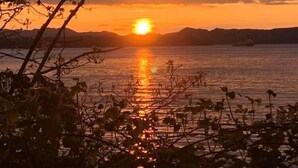 Un atardecer sobre un cuerpo de agua con montañas al fondo.