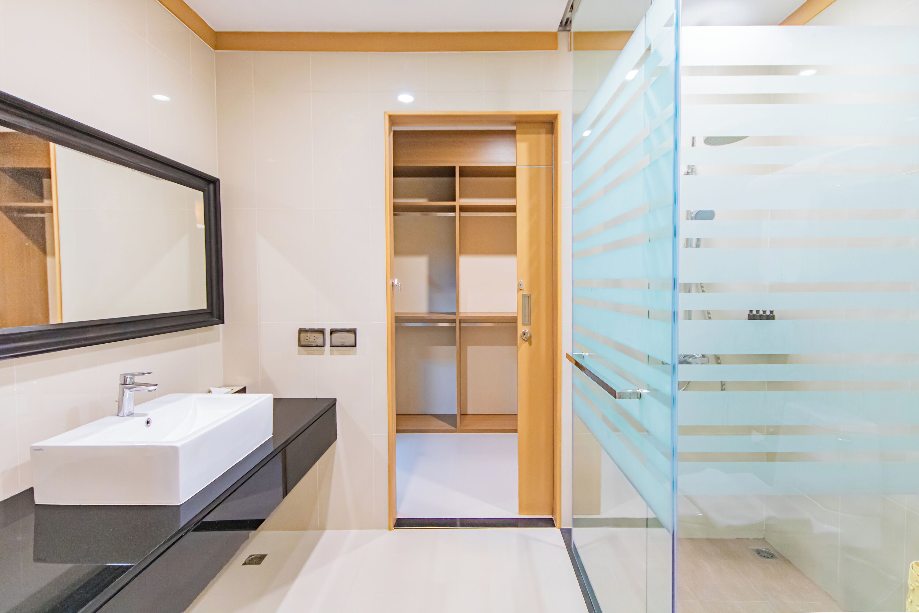 A modern bathroom with a white sink, a large mirror, and a glass-enclosed shower area.