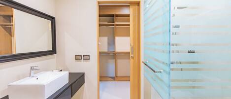A modern bathroom with a white sink, a large mirror, and a glass-enclosed shower area.