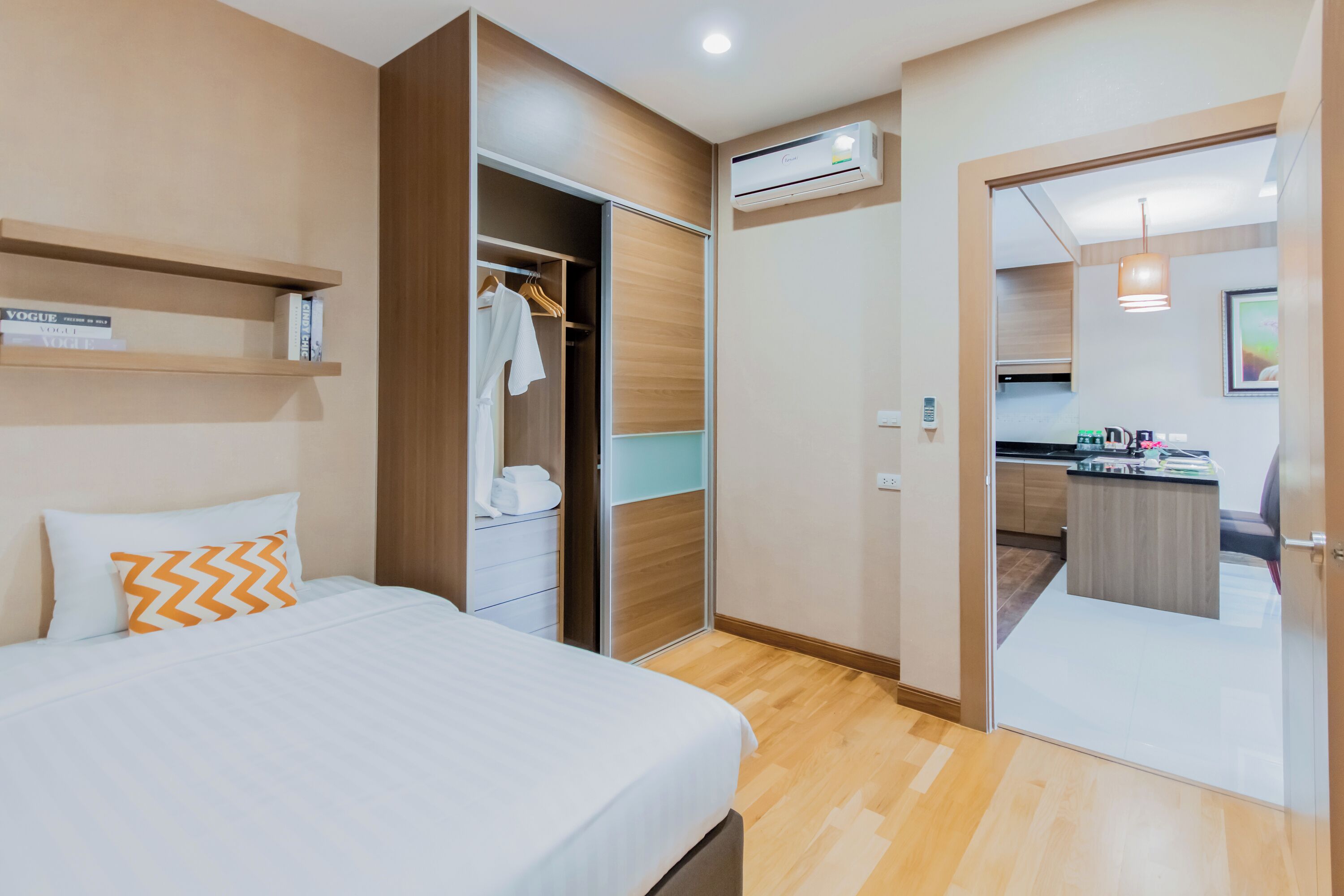 Habitación de hotel con cama, armario, kitchenette y unidad de aire acondicionado.