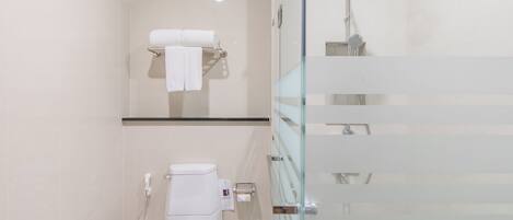 Un baño moderno con cabina de ducha de vidrio, inodoro y perchero.