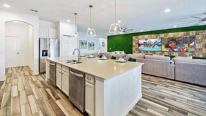 A modern kitchen with a central island, stainless steel appliances, and pendant lighting. - Mini Golf, Arcade, Huge Bedroom w/ Slide, Waterpark, Tiki Bar: Imagination Station (Davenport)