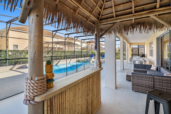 - Screened private pool with tiki bar and outdoor lounge seating  
- Relax on shaded patio with comfortable rattan furniture set  
- Vacation rental with poolside fun near Disney Orlando parks