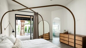 Un dormitorio moderno con una cama grande, un aparador de madera y vistas al exterior.