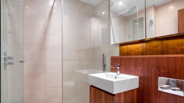 Un bagno moderno con box doccia in vetro, lavandino bianco e mobili in legno.