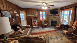 Una sala de estar acogedora con chimenea, paredes de madera y un televisor montado en la parte superior.