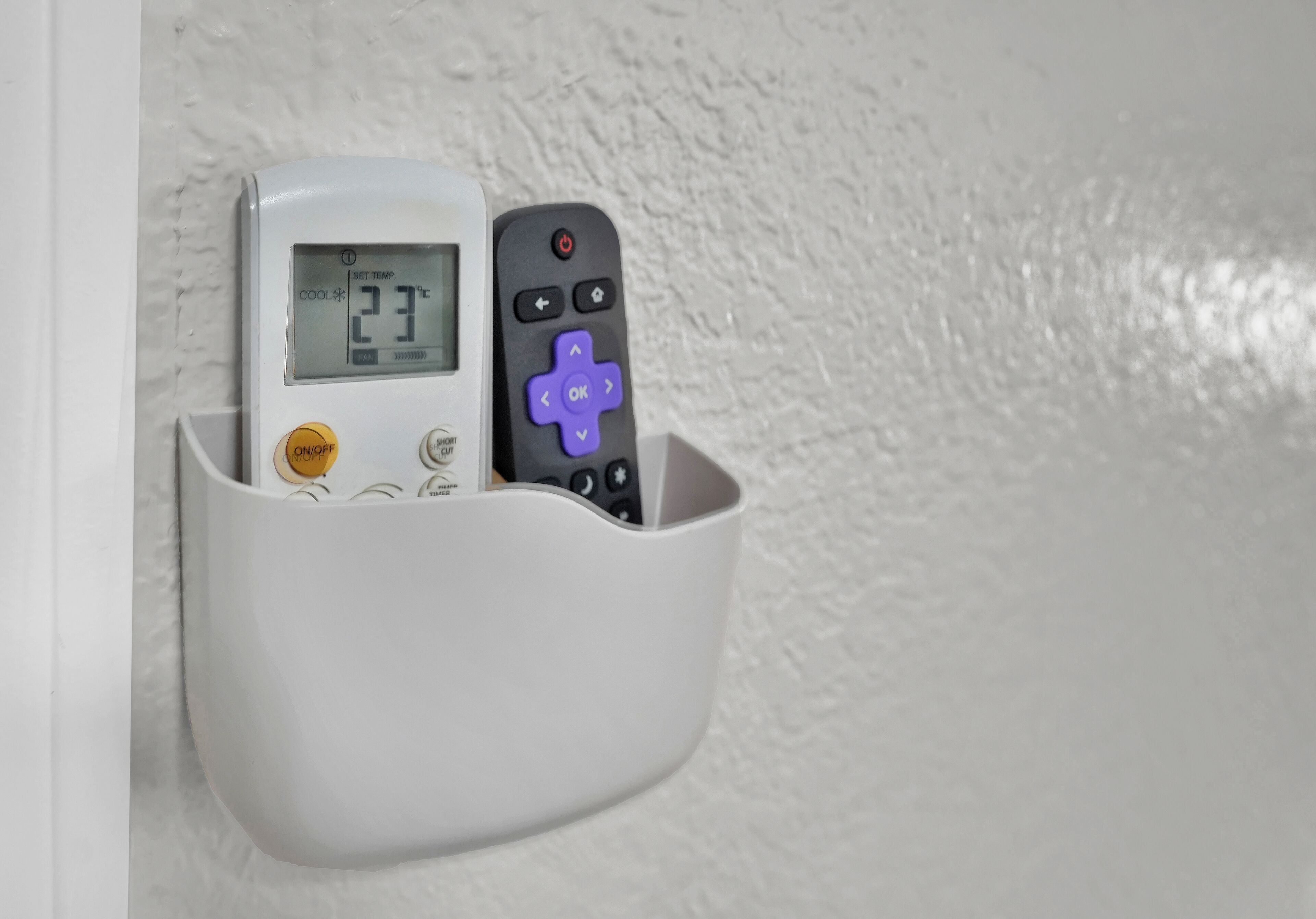 A thermostat and remote control in a white holder.