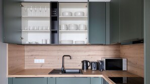 Une cuisine avec un plan de travail en bois, un évier noir et un four à micro-ondes.