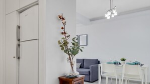 A modern living room with a grey sofa, a dining table set for four, and a wooden side table with a vase of dried flowers. - Sol Montemar 57 - Terrace, Swimming Pool, Parking, 200m from the beach (Torremolinos)