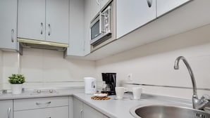 A modern kitchen with white cabinets, a stainless steel sink, a coffee maker, and a microwave. - Sol Montemar 57 - Terrace, Swimming Pool, Parking, 200m from the beach (Torremolinos)