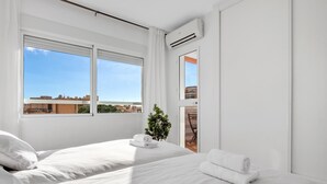 A modern hotel room with two beds, a potted plant, and a view of the cityscape. - Sol Montemar 57 - Terrace, Swimming Pool, Parking, 200m from the beach (Torremolinos)