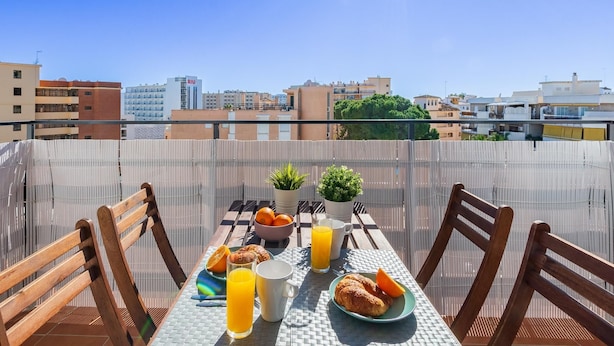 A table set with breakfast items including croissants, oranges, and orange juice, with a cityscape view in the background. - Sol Montemar 57 - Terrace, Swimming Pool, Parking, 200m from the beach (Torremolinos)