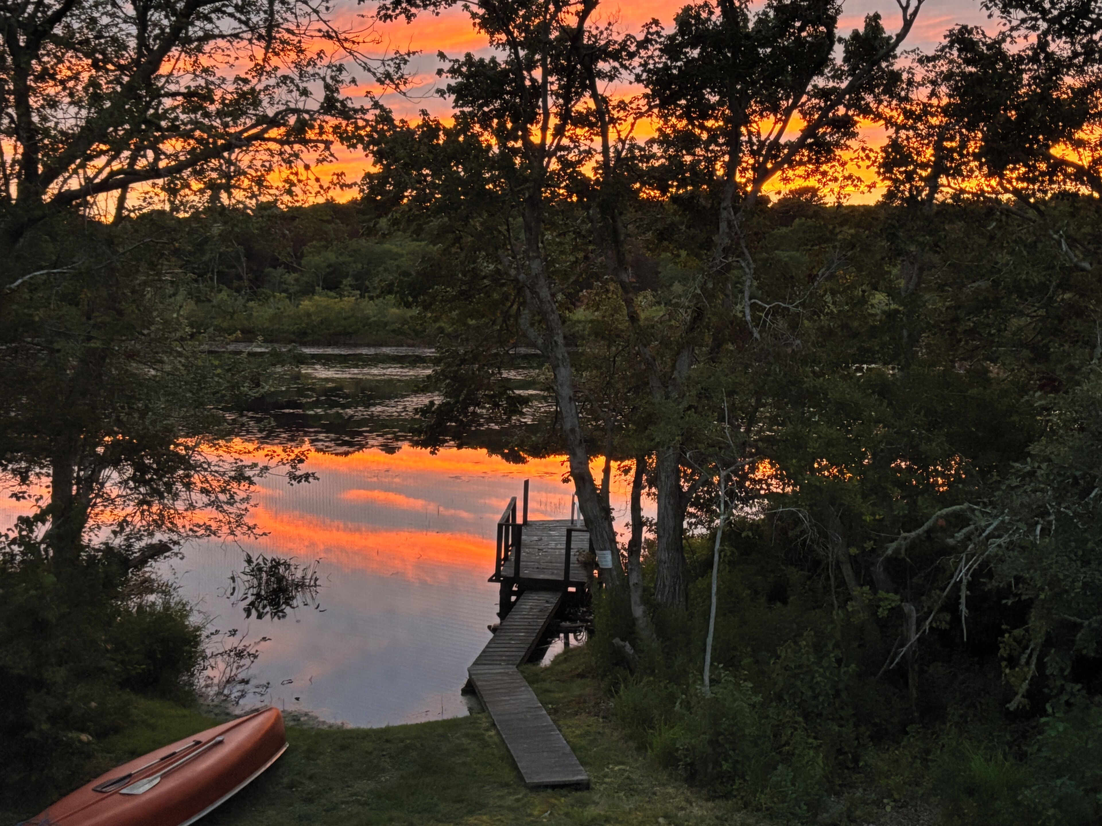 Een steiger die zich uitstrekt in een kalm waterlichaam, met een zonsondergang op de achtergrond.