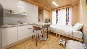 A compact room with a kitchenette, a bed, a TV, and a window with colorful curtains. - Gapyeong Jmong Choncance&camping Pension (Gapyeong)