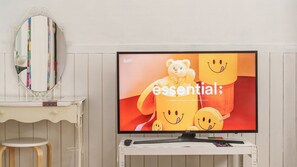 Un écran de télévision affiche un personnage d’ours sur un fond rouge, avec le mot « essentiel » écrit dessus.