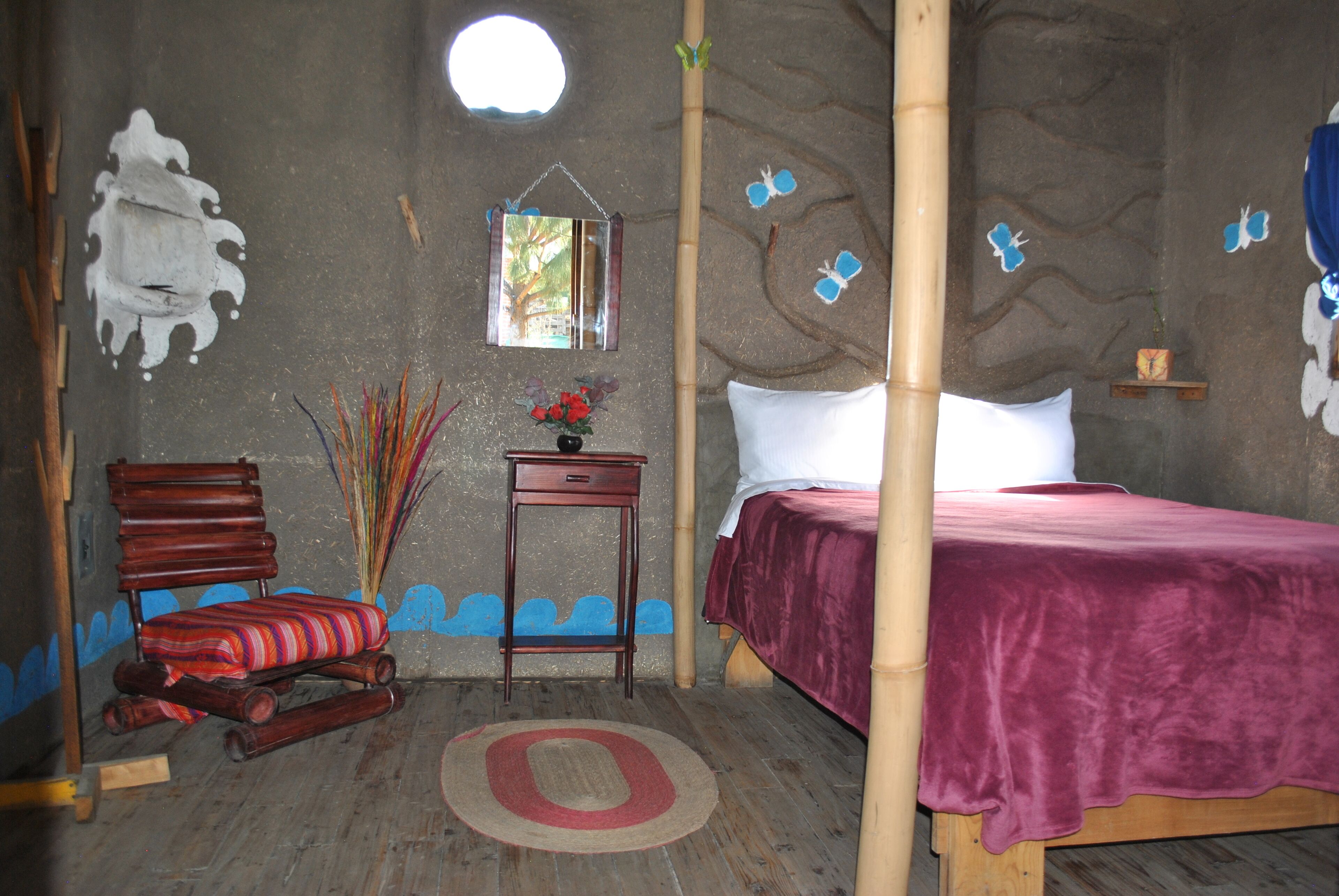 A room with a bed, a chair, a small table, and a mirror on the wall.